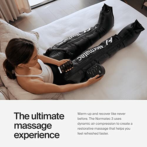 Woman using Normatec massage device on legs on bed.